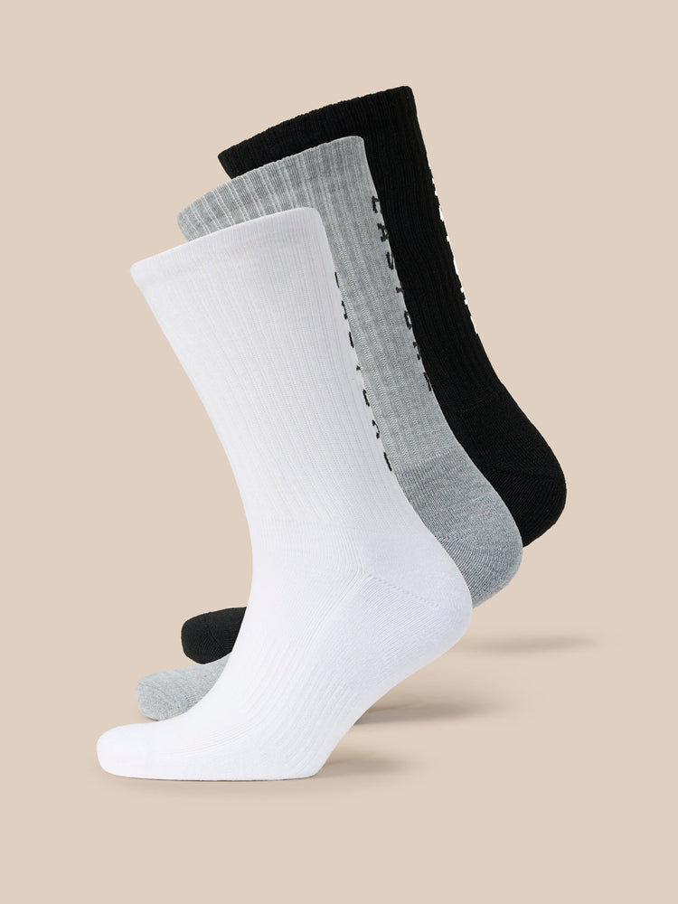 Trio of Castore X Sandham crew socks in white grey and black arranged diagonally.
