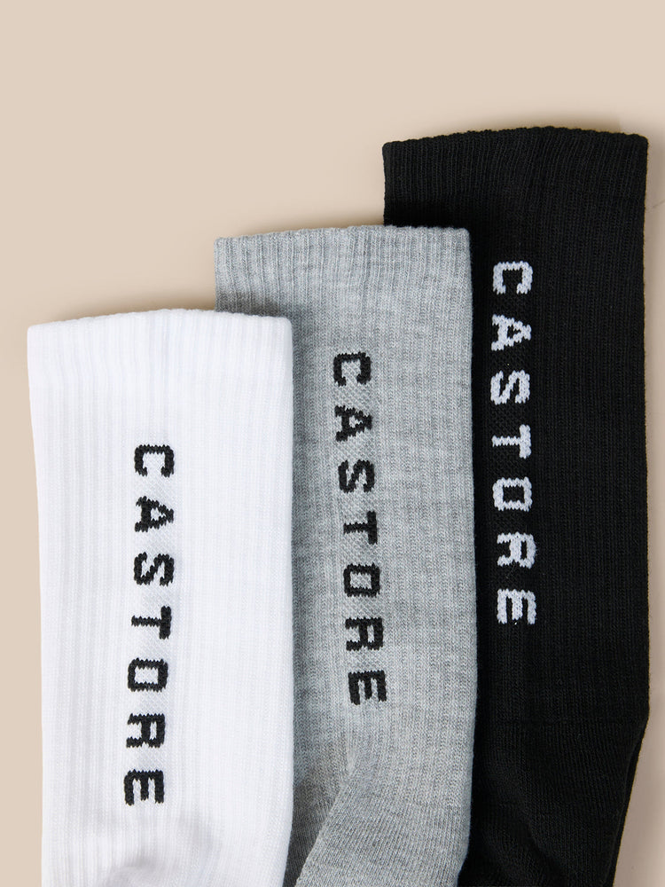 Castore X Sandham three pack crew socks in white grey and black stacked together.