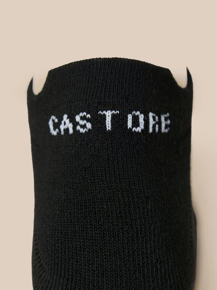 Close-up of a black Castore X Millburn trainer liner sock with white logo lettering