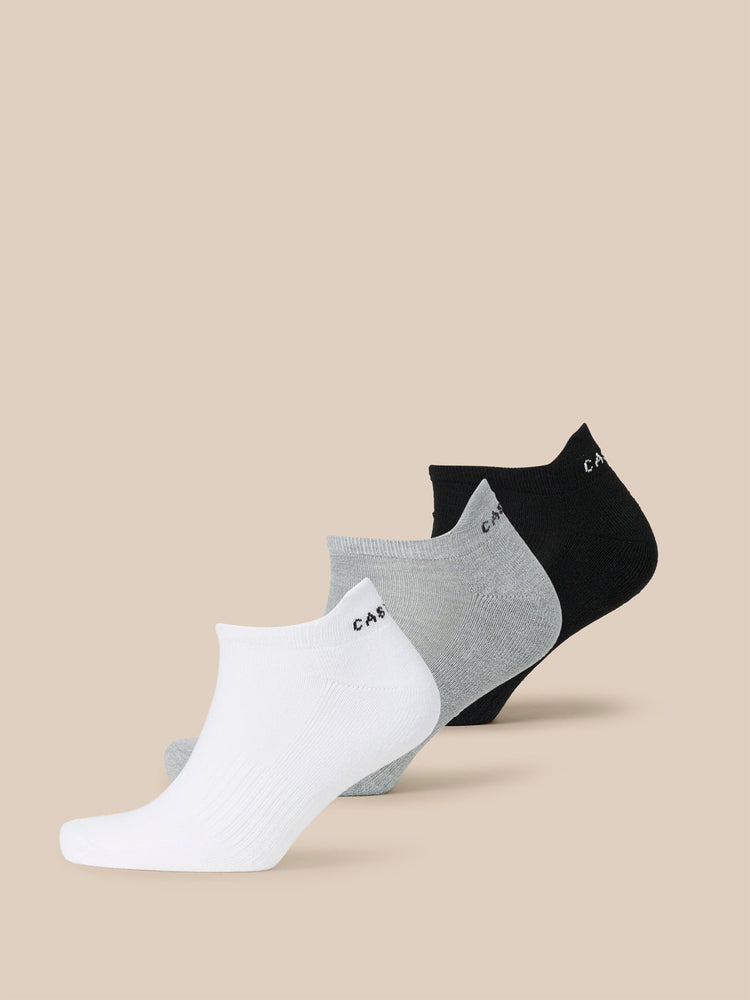 Three-pack Castore X Cowdrey trainer liner socks in white gray and black arranged in a row