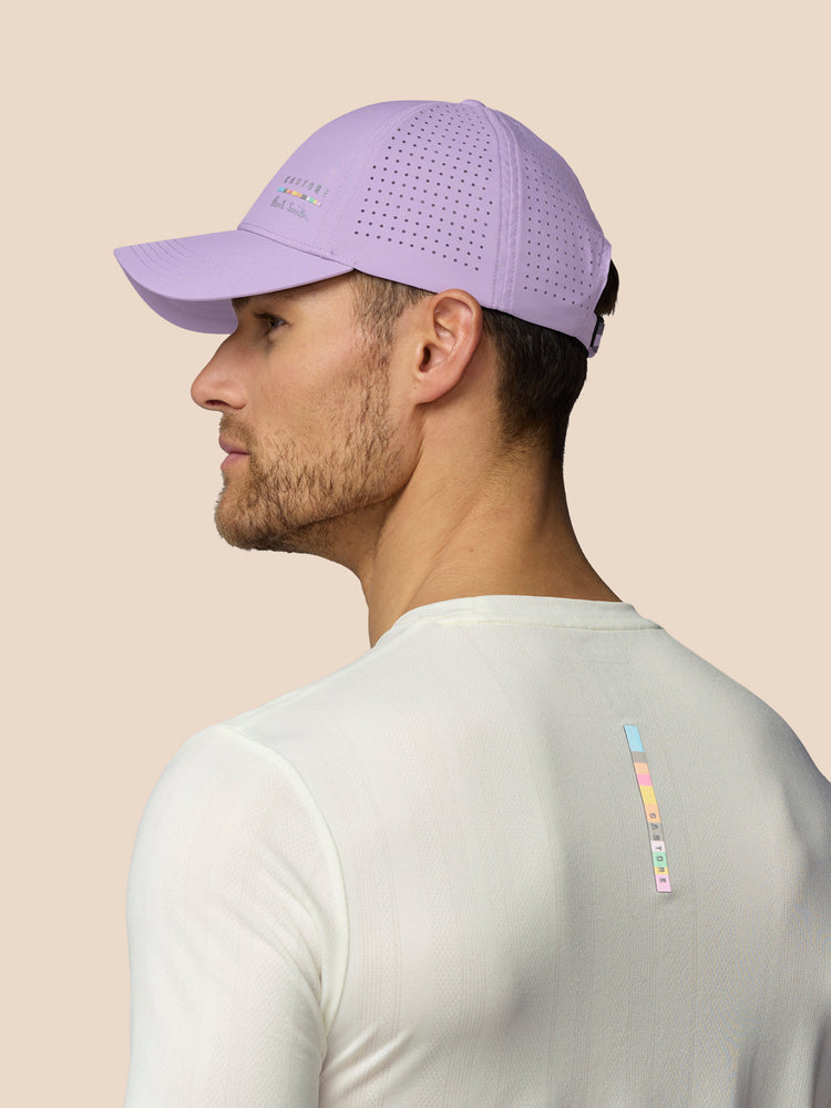 Man wearing a purple cap and white shirt with colorful design on beige background