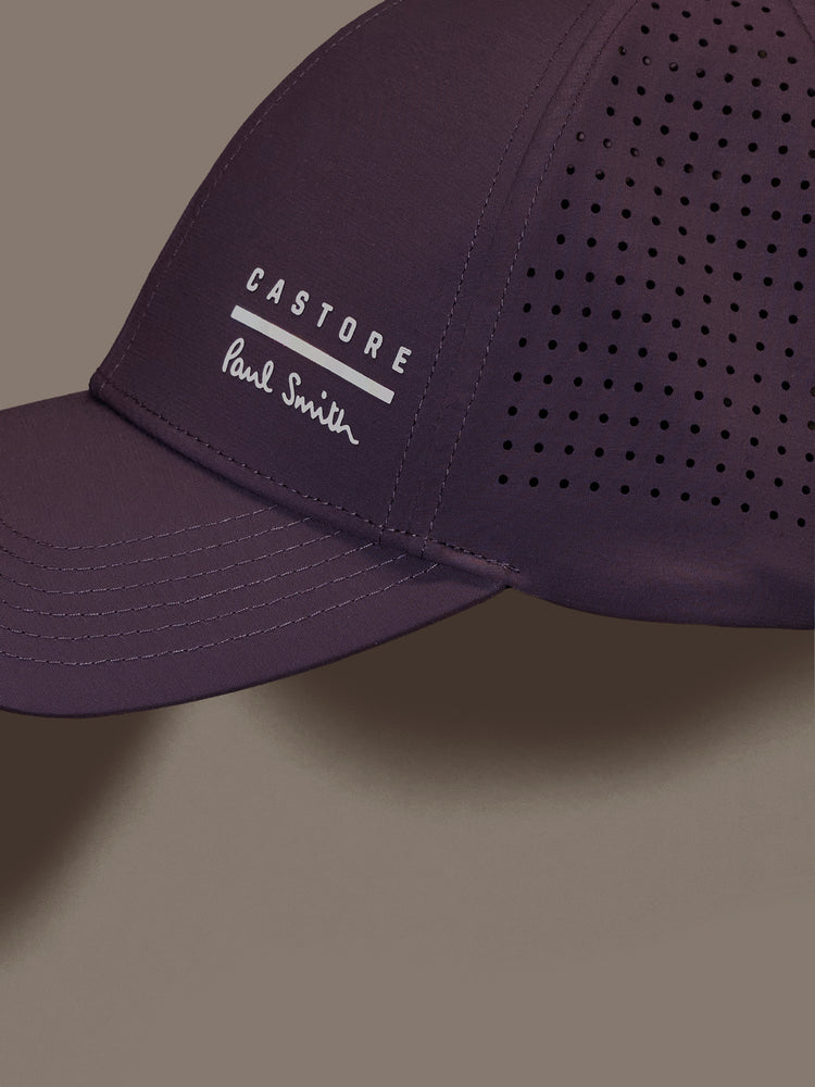 Mauve cap with 'Castore' and 'Paul Smith' logos on a gray background