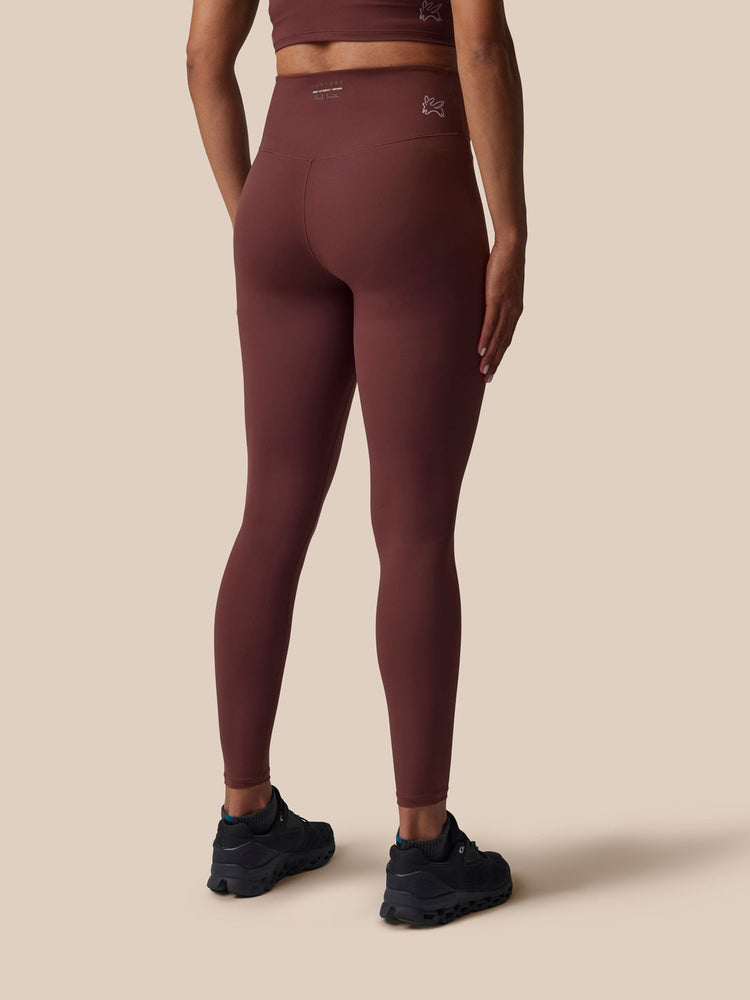 Person wearing maroon leggings on a beige background