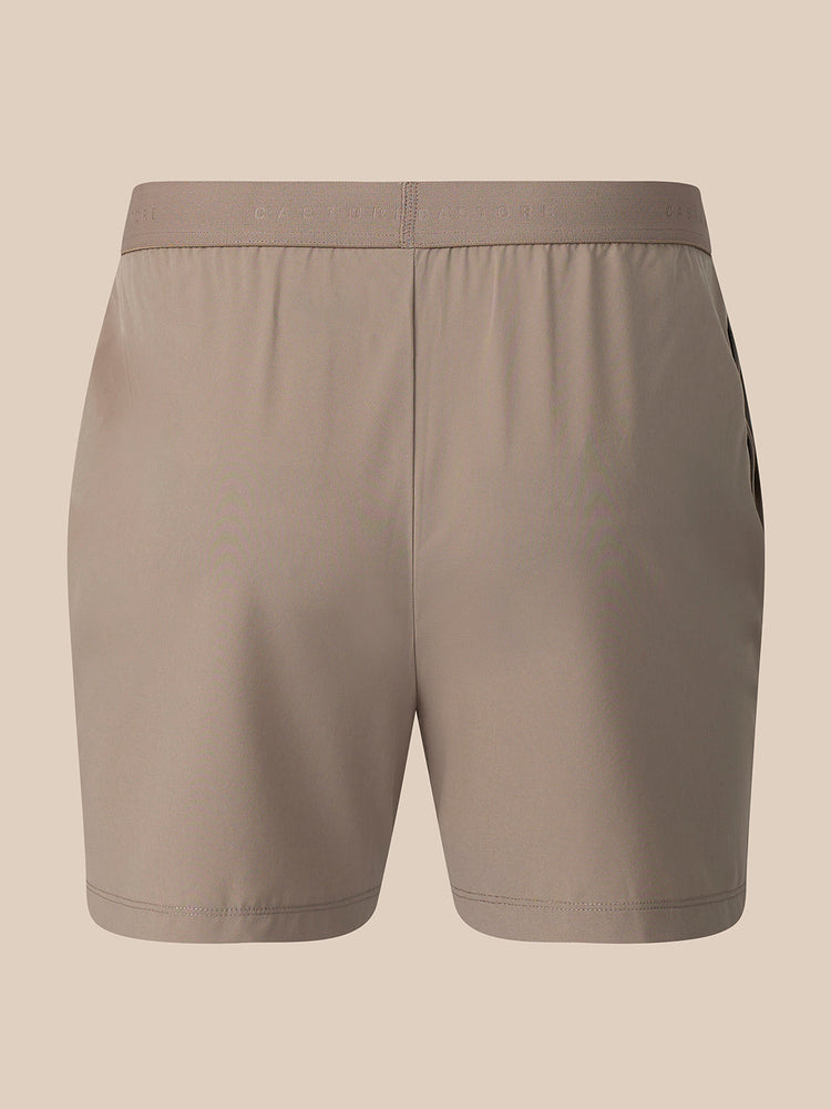 A pair of athletic shorts in a solid taupe color, shown from the back against a solid beige background.