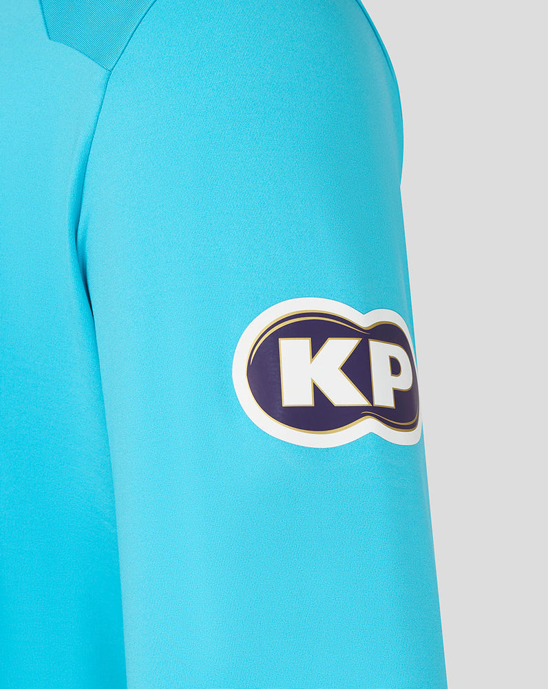 Close-up of a blue shirt with a KP logo on the sleeve against a white background