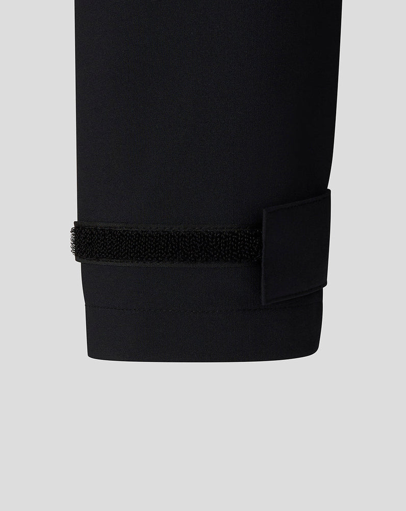 Close-up of a black pants cuff with a elastic band on a light gray background
