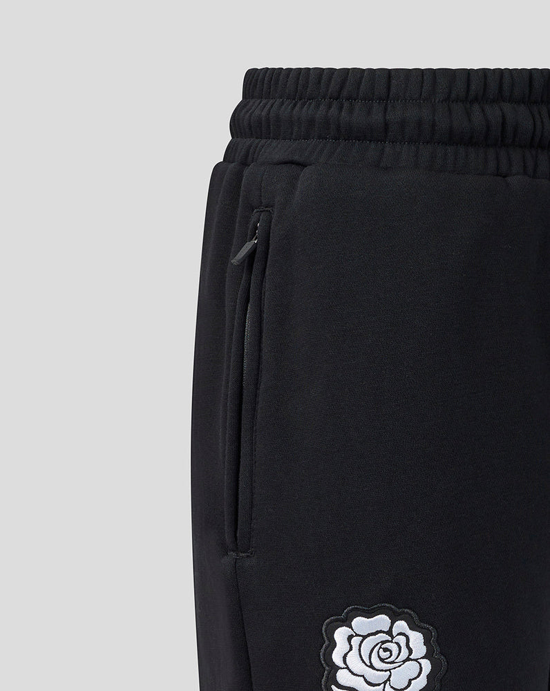 Black sweatpants with a white rose design on a light gray background