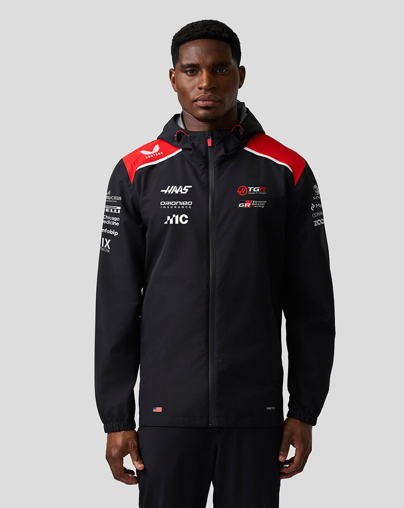 Person wearing a black jacket with red and white accents on a gray background